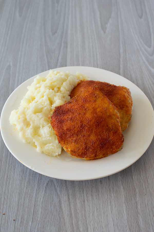 Grill chicken for passover on a white plate with mashed potatoes on a white wood background