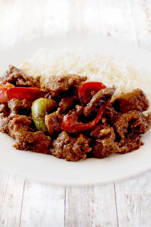 Kosher Pepper Steak with white rice on a white dish on a white wood background