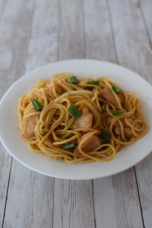kosher chicken lo mein on a white plate on a white wood background