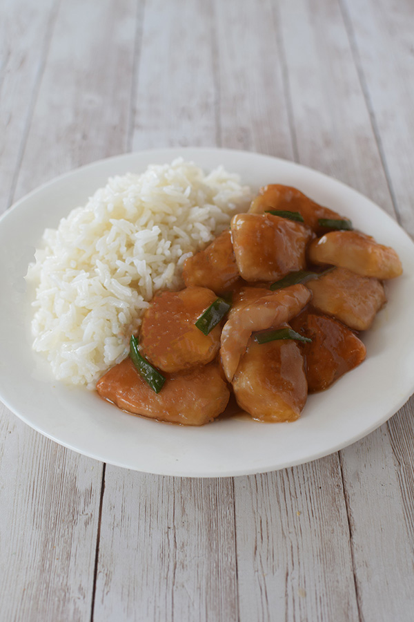mongolian chicken with white rice on a white place on a white wood background