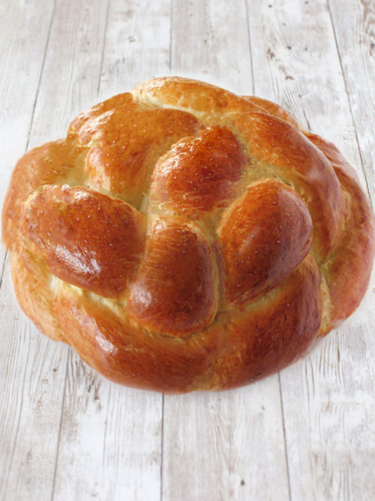 Round braided challah on a white wood table