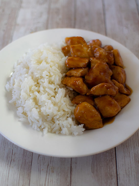 teriyaki chicken with white rice on a white plate on a white wood background