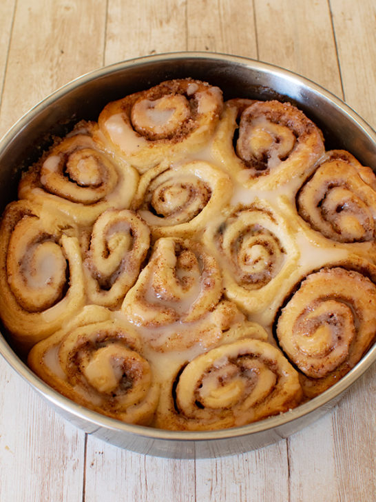 Dairy Free Cinnamon Rolls in a round baking pan on a white wood table