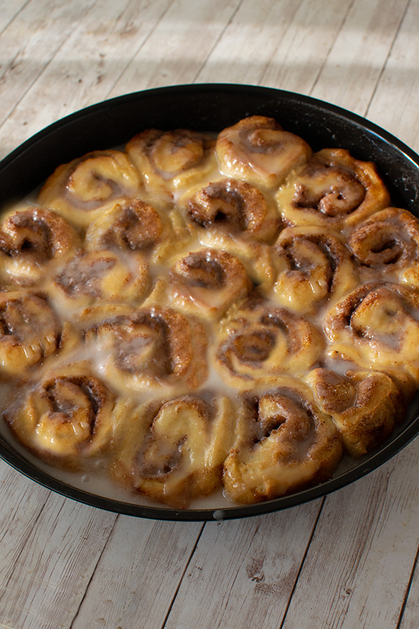 Dairy Free Chocolate sweet Rolls in a round baking pan on a white wood table