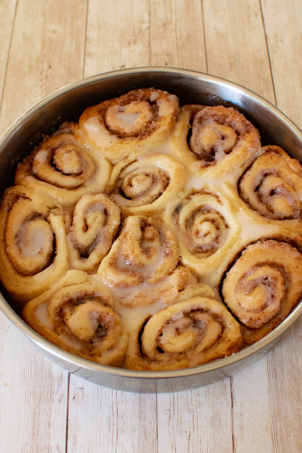 Dairy Free Cinnamon Rolls in a round baking pan on a white wood table