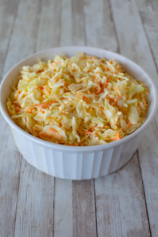 Sweet Deli Cole slaw with shredded cabbage and carrots in a white bowl on a wood background