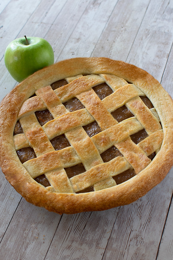 Baked mock apple pie with a green apple on a white wood table