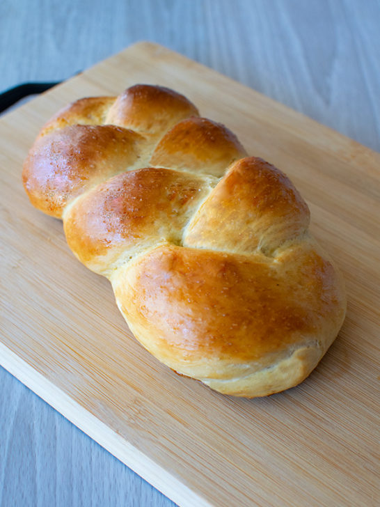 Fluffy Water Challah on a bread board on a white wood table