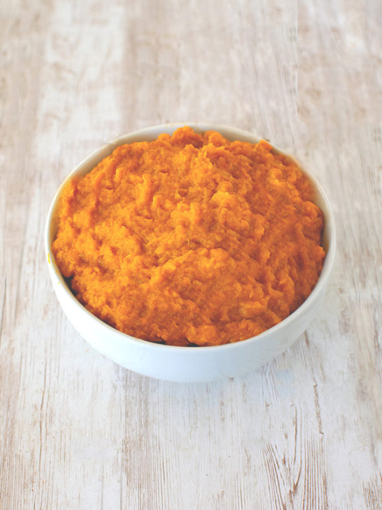 pure Butternut squash puree in a white bowl on a white wood table
