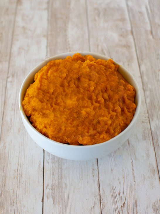 Pure Sweet Potato Puree in a white bowl on a white slatted wood table