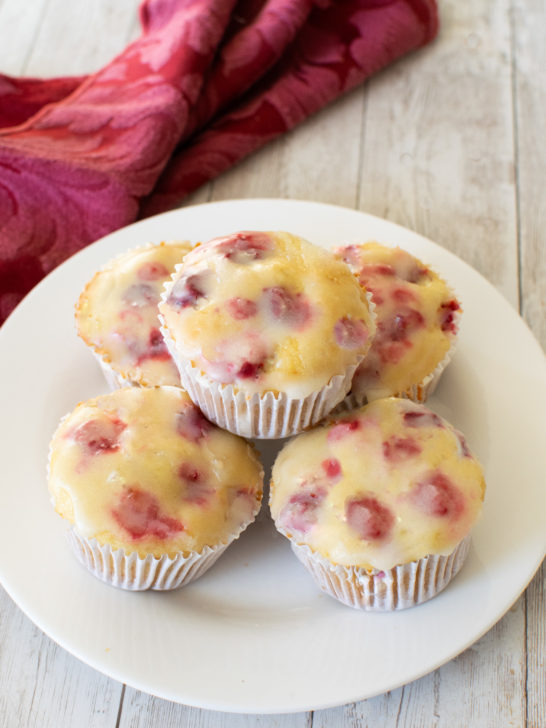 Easy Dairy-Free Cranberry-Orange Muffins on a white plate near a red cloth napkin on a white wood table