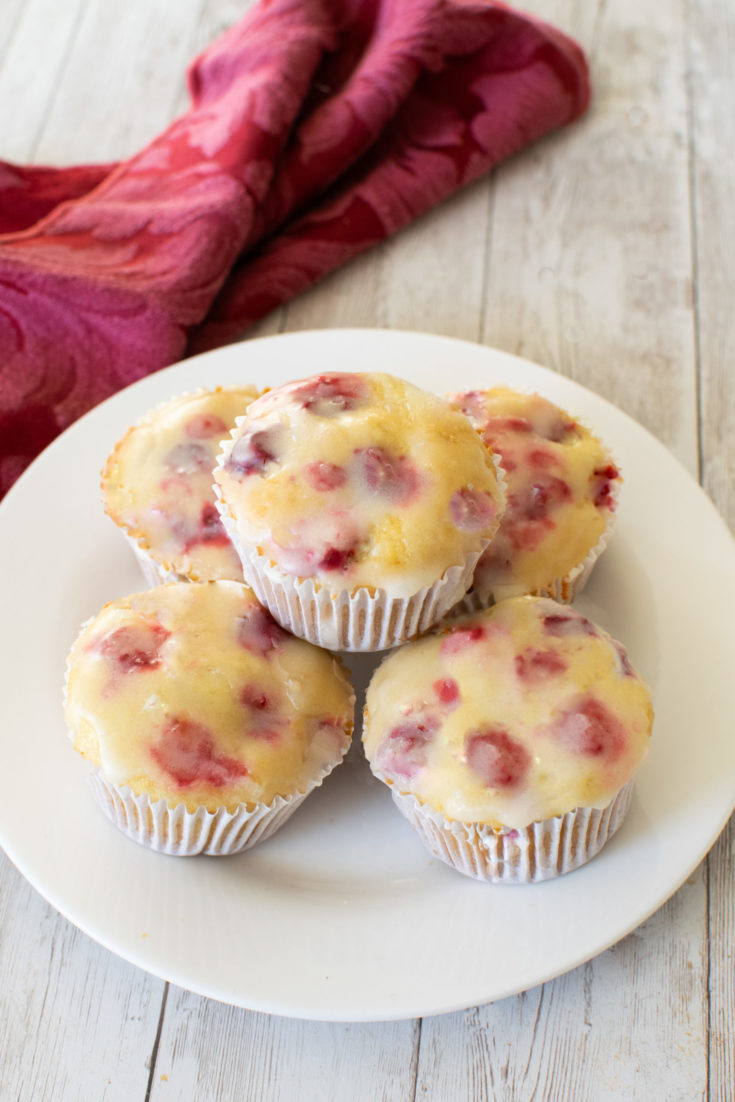 Easy Dairy-Free Cranberry-Orange Muffins on a white plate near a red cloth napkin on a white wood table