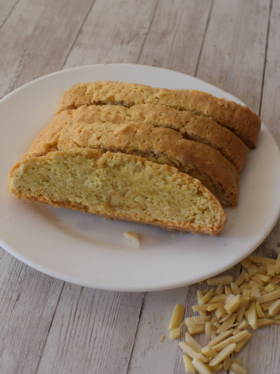 Easy Dairy-Free Mandel Bread with almond slices on a white plate on a white wood table with almond slices nearby