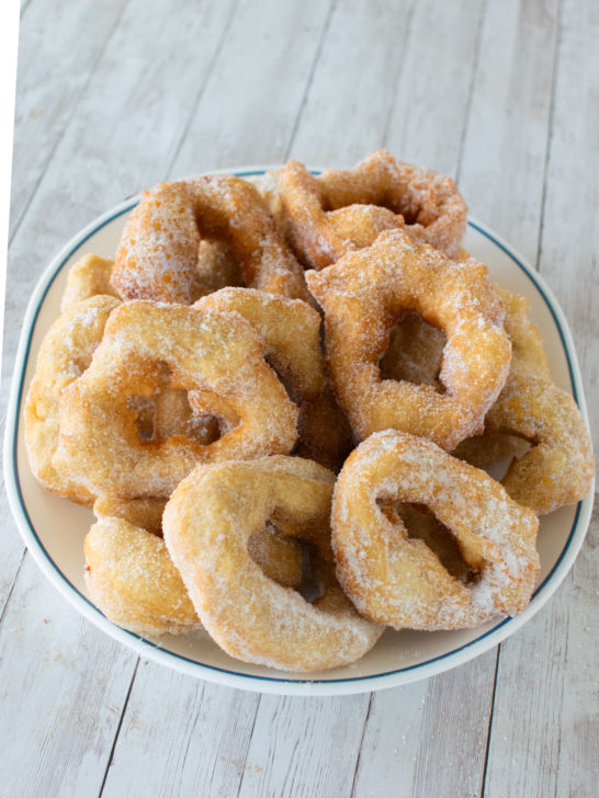 Easy moroccan doughnuts (sfinge) on a white plate with a blue rim on a white wood background.