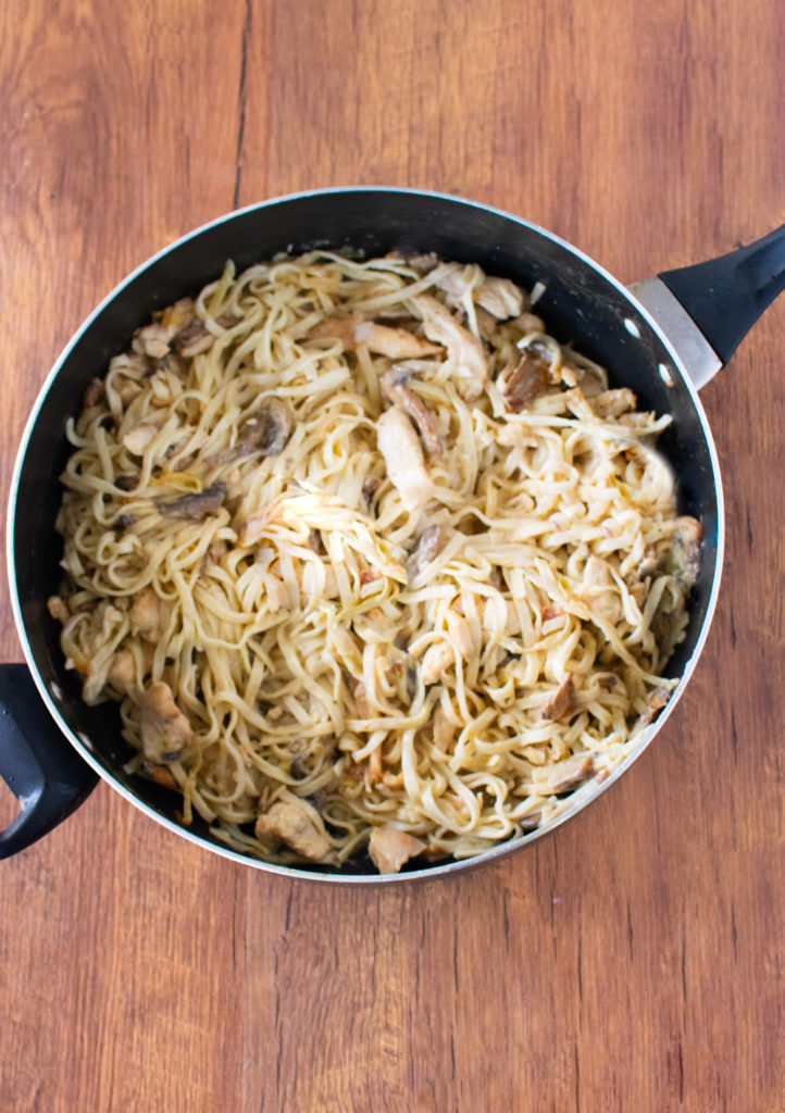 Easy Chicken Stroganoff with Noodles in a pan with handles on a dark wood background