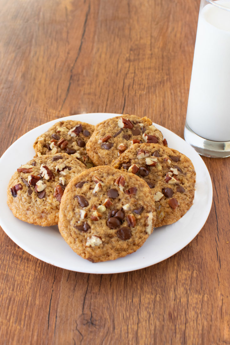 Easy Oatmeal Chocolate Chip Pecan Cookies on a white plate near a clear glass of milk on a dark wood table