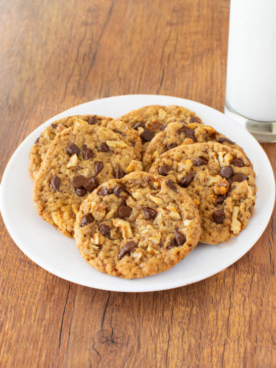 Easy Oatmeal Chocolate Chip Walnut Cookies on a white plate near a clear glass of milk on a dark wood table