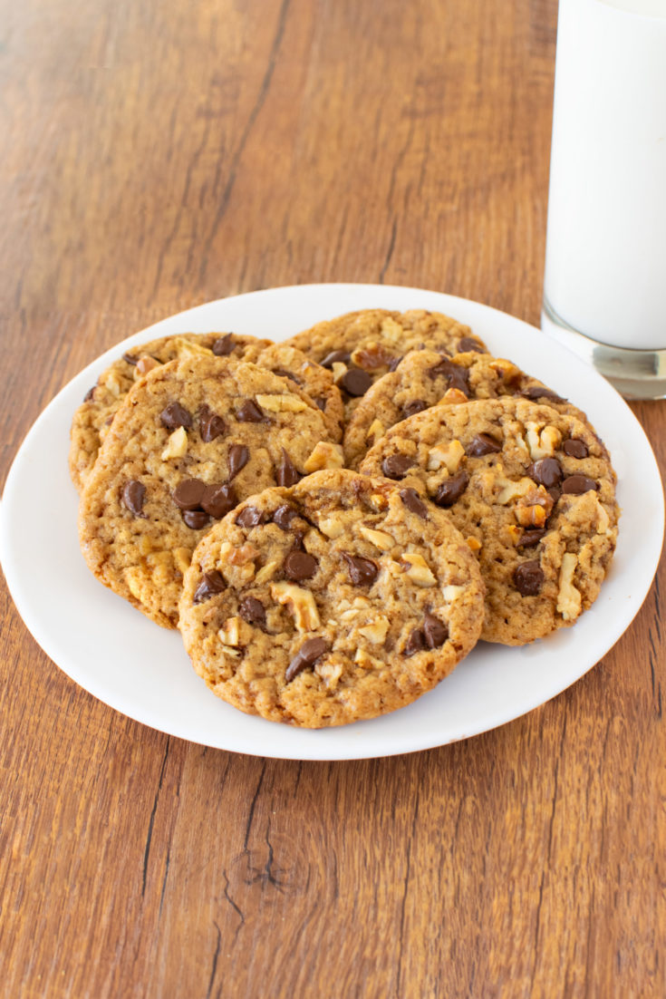 Easy Oatmeal Chocolate Chip Walnut Cookies on a white plate near a clear glass of milk on a dark wood table