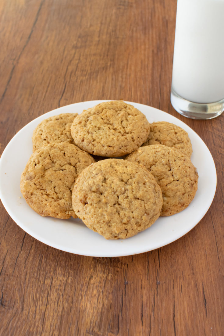 Easy Plain Oatmeal Cookies on a white plate on a dark wood table with a clear glass of milk nearby