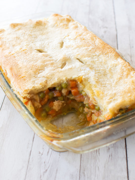 Easy Dairy-Free Chicken Pot Pie Casserole with a piece missing in a glass baking dish on a white wood background